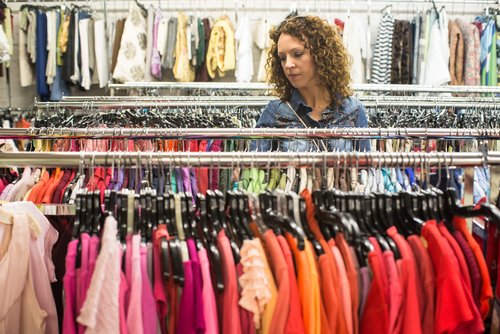 Woman browses racks of used clothing for sale Bank & Vogue
